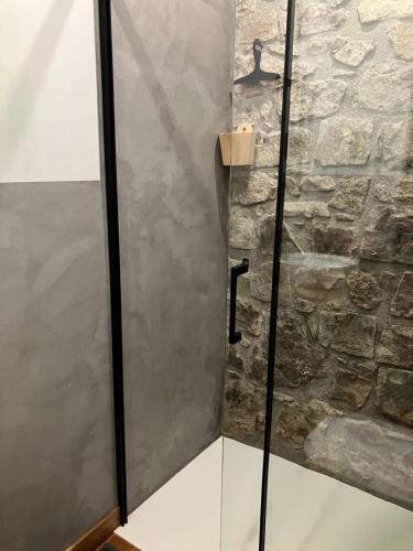 La salle de bains est pourvue d'une douche et d'un mur en pierre. dans l'établissement Charmant appartement cosy, à Saint-Raphaël