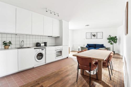 - une cuisine et une salle à manger avec des placards blancs et une table dans l'établissement Appartements Mairie de Pantin, à Pantin