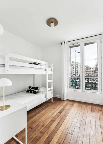 - une chambre avec des lits superposés blancs et une fenêtre dans l'établissement Appartements Mairie de Pantin, à Pantin