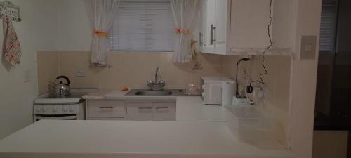 a white kitchen with a sink and a counter top at Macaw Villa in Mossel Bay
