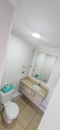 a bathroom with a toilet and a sink and a mirror at serrano 932 iquique departamento in Iquique