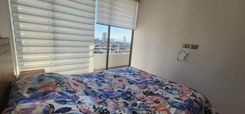 a bedroom with a bed and a large window at serrano 932 iquique departamento in Iquique