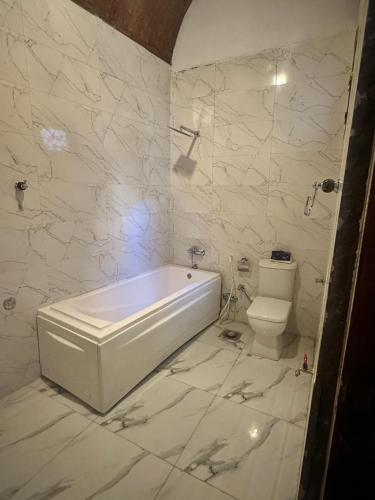 a white bathroom with a tub and a toilet at ZAIN PALACe in Jazīrat al ‘Awwāmīyah