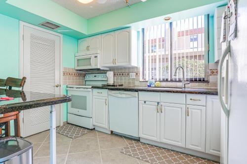a kitchen with white appliances and a window at Comfortable Jensen Beach Condo with Pool View! in Jensen Beach