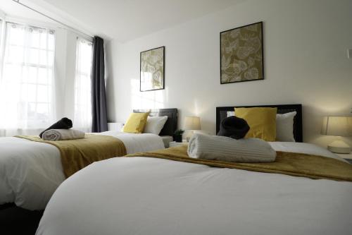 2 Betten in einem Schlafzimmer mit weißen Wänden und gelben Kissen in der Unterkunft - WINTER SALE - Entire 2-Bedroom Apartment in the bustling City Centre WIFI TRAIN & BUS STATION in Colchester