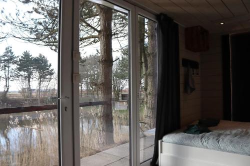 a bedroom with a sliding glass door with a view at The waterfront & birds nest in Evergem