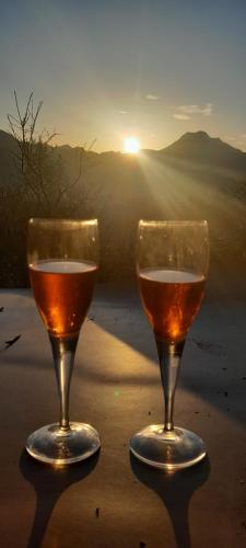 two glasses of wine sitting on a table with the sunset at La fatina Lodge in Barga
