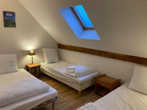 Cette chambre mansardée comprend 2 lits et une lucarne. dans l'établissement Appartement duplex 8 pers à Super-Besse avec wifi et piscine chauffée, à Besse-et-Saint-Anastaise