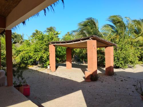 a pavilion on a beach with palm trees in the background at Hôtel Nanaay in Palmarin