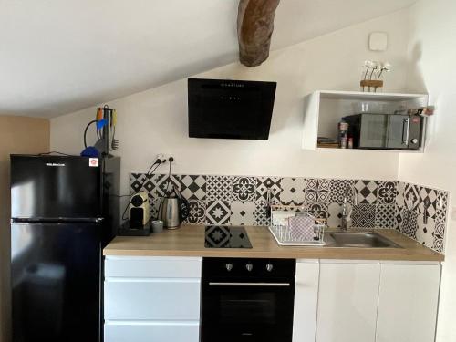 La cuisine est équipée d'un réfrigérateur noir et d'un évier. dans l'établissement Chez Jean-Yves et Zoé - LE SAINT ANDRÉ - Au calme, Très propre, Proche parkings, Clim, à Niort