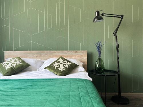 a green bedroom with a bed with a lamp and pillows at ADT apartments in Almaty