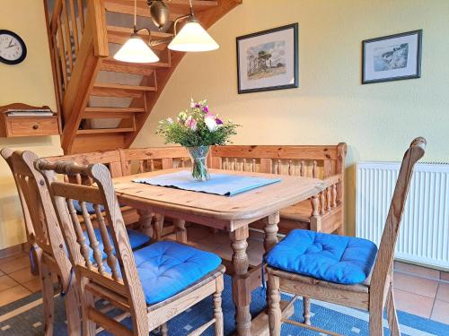 a dining room table with chairs and a vase of flowers at Achtern Diek Haus 12d Wohnung 6 in Müggenburg