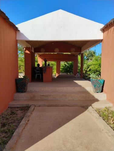 a pavilion with a person sitting in a chair under it at Hôtel Nanaay in Palmarin