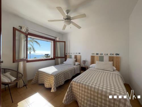 two beds in a room with a window and a fan at VH CostaBlanca - EVA in Benissa