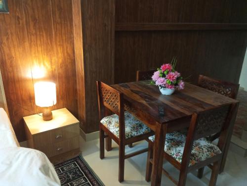 una mesa de madera con 2 sillas y un jarrón de flores. en Cozy nook stay - Nearest stay from ram mandir 1 km, en Ayodhya