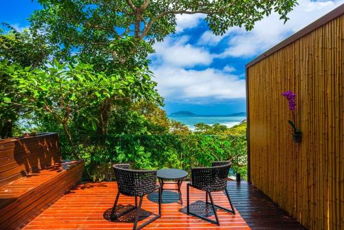 a patio with three chairs and a table on a deck at Nosso Mar in Florianópolis