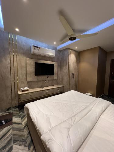 a bedroom with a large white bed and a flat screen tv at Courteous Hotel in Islamabad
