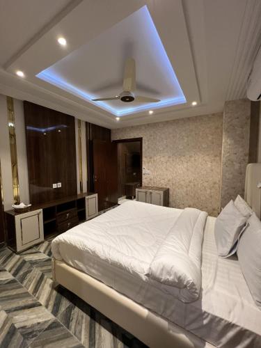 a bedroom with a white bed with a ceiling fan at Courteous Hotel in Islamabad