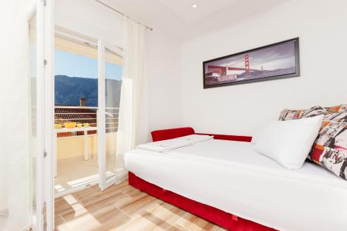 a white bedroom with a bed and a balcony at Apartments Blue Sea in Kotor