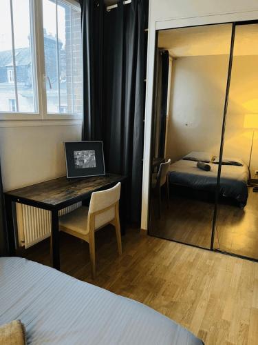 Cette chambre comprend un bureau, un lit et un miroir. dans l'établissement Appartement Hyper Centre Rouen, à Rouen