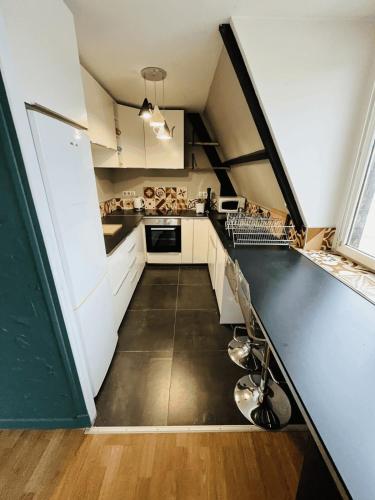 une cuisine mansardée avec des placards blancs et un comptoir dans l'établissement Appartement Hyper Centre Rouen, à Rouen