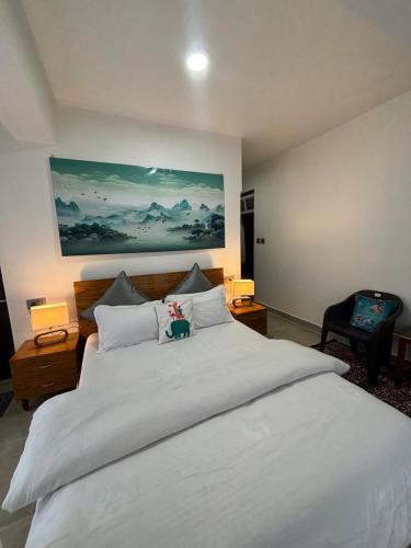a bedroom with a large white bed with a painting on the wall at Arcane viewfinder homestay in Gangtok