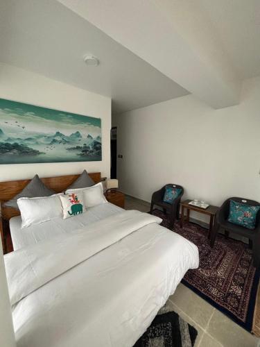 a bedroom with a large white bed and two chairs at Arcane viewfinder homestay in Gangtok