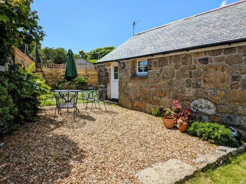 a patio with a table and chairs in front of a building at Bleujenn barn, delightful home near stunning beach and walks in Penzance