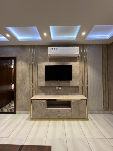 a living room with a flat screen tv and a table at Courteous Hotel in Islamabad