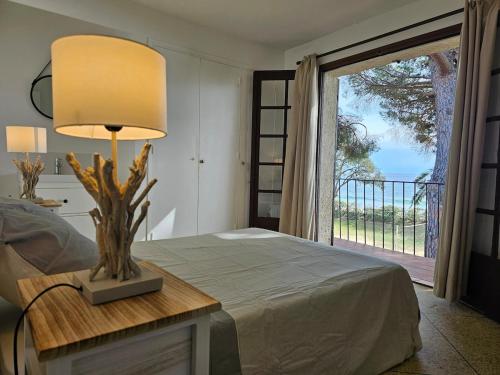 une chambre avec un lit avec une lampe sur une table dans l'établissement Villa Familiale Pied dans l'eau accès direct à la plage, à Cavalaire-sur-Mer