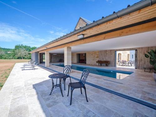 un patio avec une table et des chaises à côté d'une piscine dans l'établissement Gite de luxe, à Groléjac