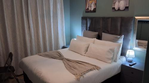 a bedroom with a bed with white sheets and pillows at SIMICON Guesthouse in Witbank