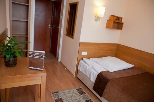 a small bedroom with a bed and a table at Sanatorium Budowlani Szczawnica in Szczawnica