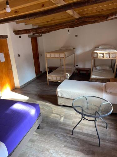 a room with two beds and a table in it at Hotel La Cochera in San Pedro de Atacama