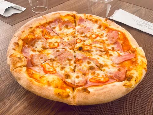 a pizza with ham and cheese on a table at Hotel Măgura Jina in Jina