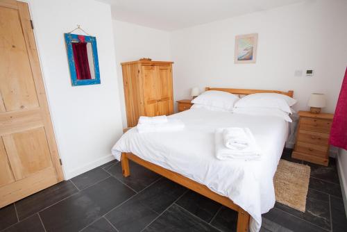 a bedroom with a bed with white sheets and pillows at Bleujenn barn, delightful home near stunning beach and walks in Penzance