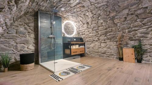 une salle de bain avec une douche en verre dans un mur en pierre dans l'établissement Chalet 4 p Le Chardon du Roc, à La Côte dʼArbroz