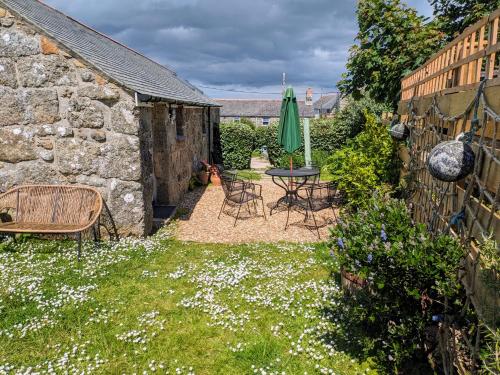 a garden with a table and chairs and a umbrella at Bleujenn barn, delightful home near stunning beach and walks in Penzance