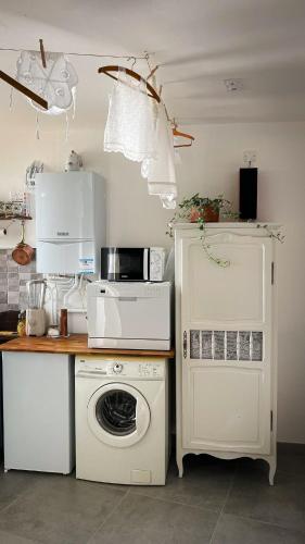 une cuisine avec un lave-linge et un micro-ondes dans l'établissement La Blanchisserie, à Mazé