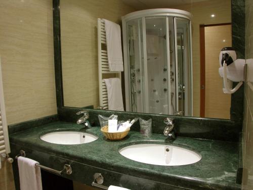 a bathroom with two sinks and a large mirror at Hotel II Castillas Ávila in Ávila