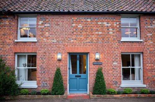 una casa in mattoni con porta blu e finestre di Grints Cottage a Burnham Thorpe