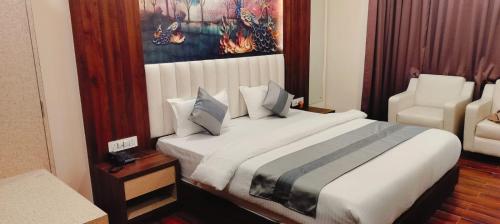 a hotel room with a large bed and a chair at SB INTERNATIONAL Hotel & Banquet in Dhanbād