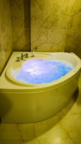 a green tub with blue water in a bathroom at SB INTERNATIONAL Hotel & Banquet in Dhanbād