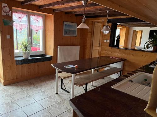 - une salle à manger avec une table et un banc dans l'établissement ferme des grands blaise, à La Bresse