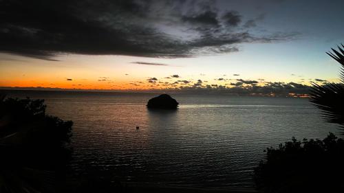 a sunset over a body of water with a rock in it at Beachfront at Cabo Rojo in Cabo Rojo