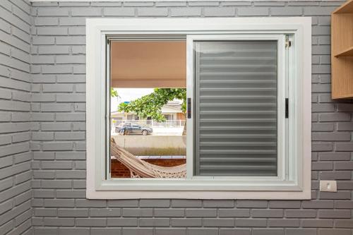 a window with a shutter in a brick wall at Memora Guesthouse Pontal do Paraná - Casa inteira ou Quartos a duas quadras da praia e próxima a Ilha do Mel in Pontal do Paraná