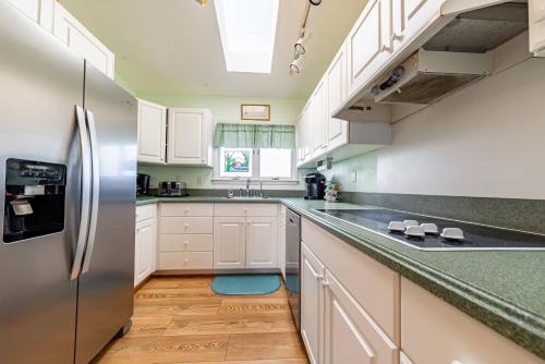 a kitchen with white cabinets and a stainless steel refrigerator at Duck R Way in Duck
