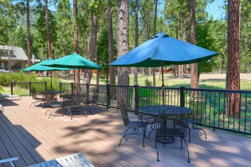 a deck with tables and chairs and umbrellas at The Terry Cabin in Wawona