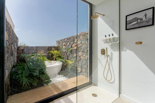 La salle de bains est pourvue d'une douche en verre et d'une baignoire. dans l'établissement Villa Calma by Aura Collection, à Lajares