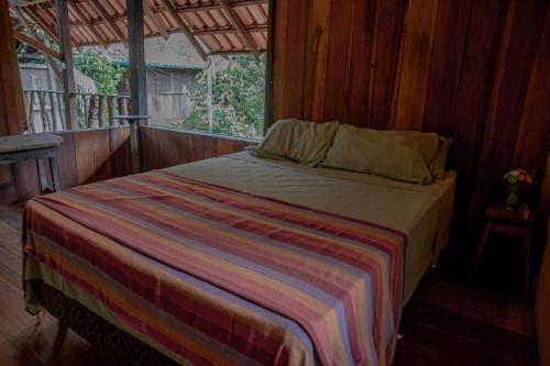 a bedroom with a bed with a striped blanket at Suíte Curuaçu in Santarém